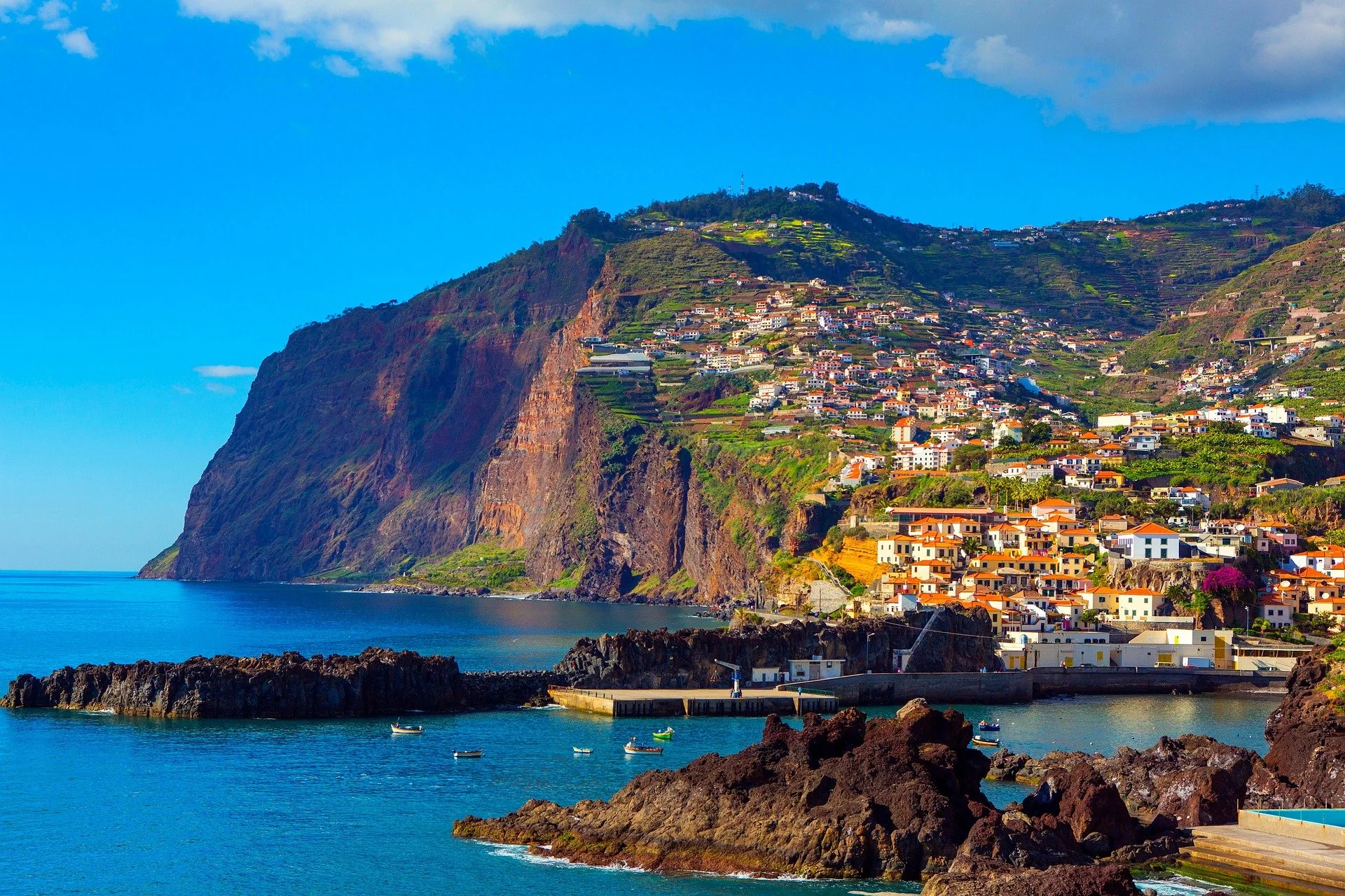 Falaises vertigineuses et versants verdoyants de Madère plongeant dans l'Atlantique, baie de Funchal en contrebas